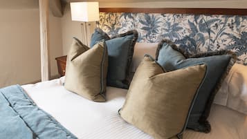 Una cama bien hecha con colcha a rayas blancas y azules, dos almohadas beige y una almohada azul con borde oscuro.