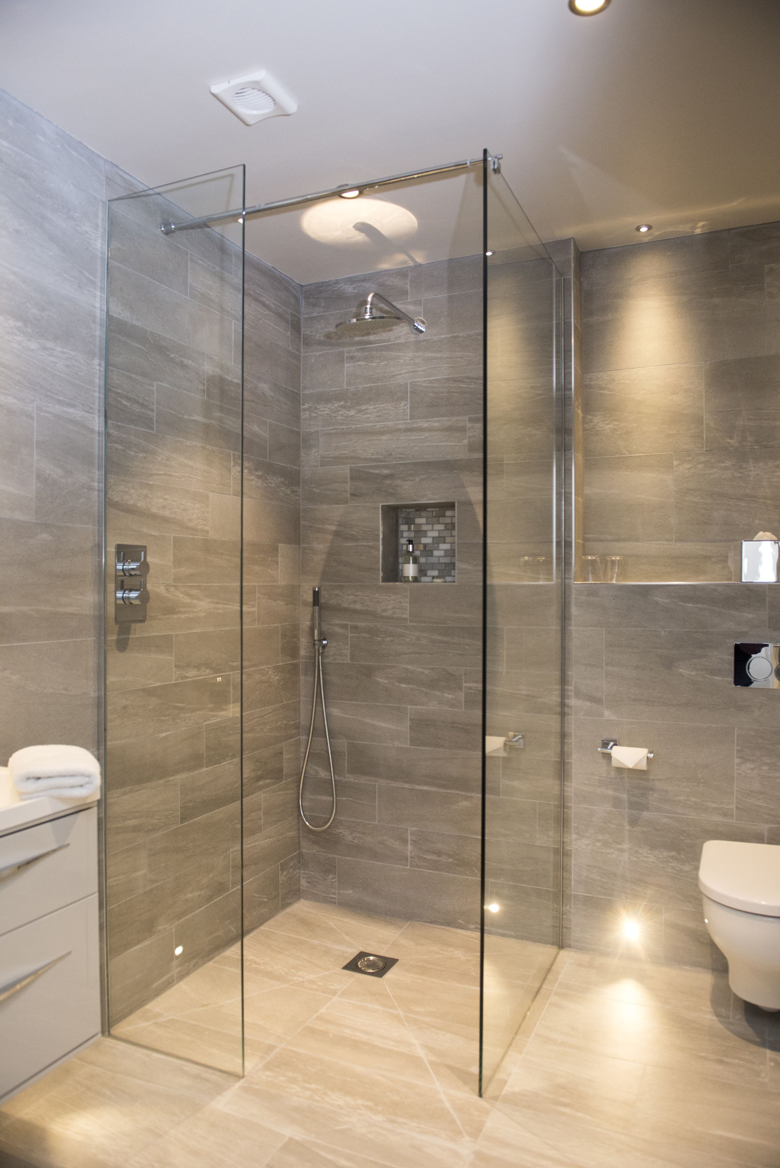 A modern bathroom with a glass-enclosed shower, a toilet, and a sink.