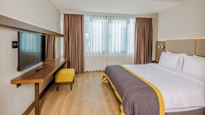 A hotel room with a bed, a TV, a desk, and a window with curtains. - Nearport Hotel Sabiha Gokcen Airport (Istanbul)