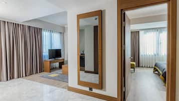 A modern hotel room with a large mirror, a television, a sofa, and a bed.