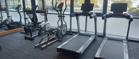 A gym with treadmills, stationary bikes, and a rowing machine.