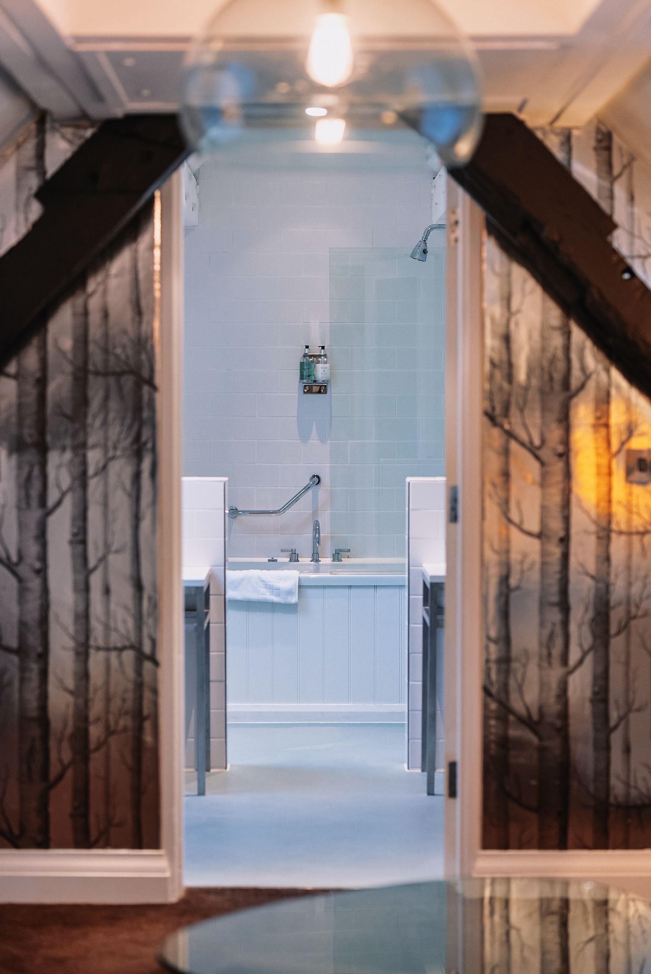 Een badkamer met een betegelde muur, een wastafel en een spiegel.