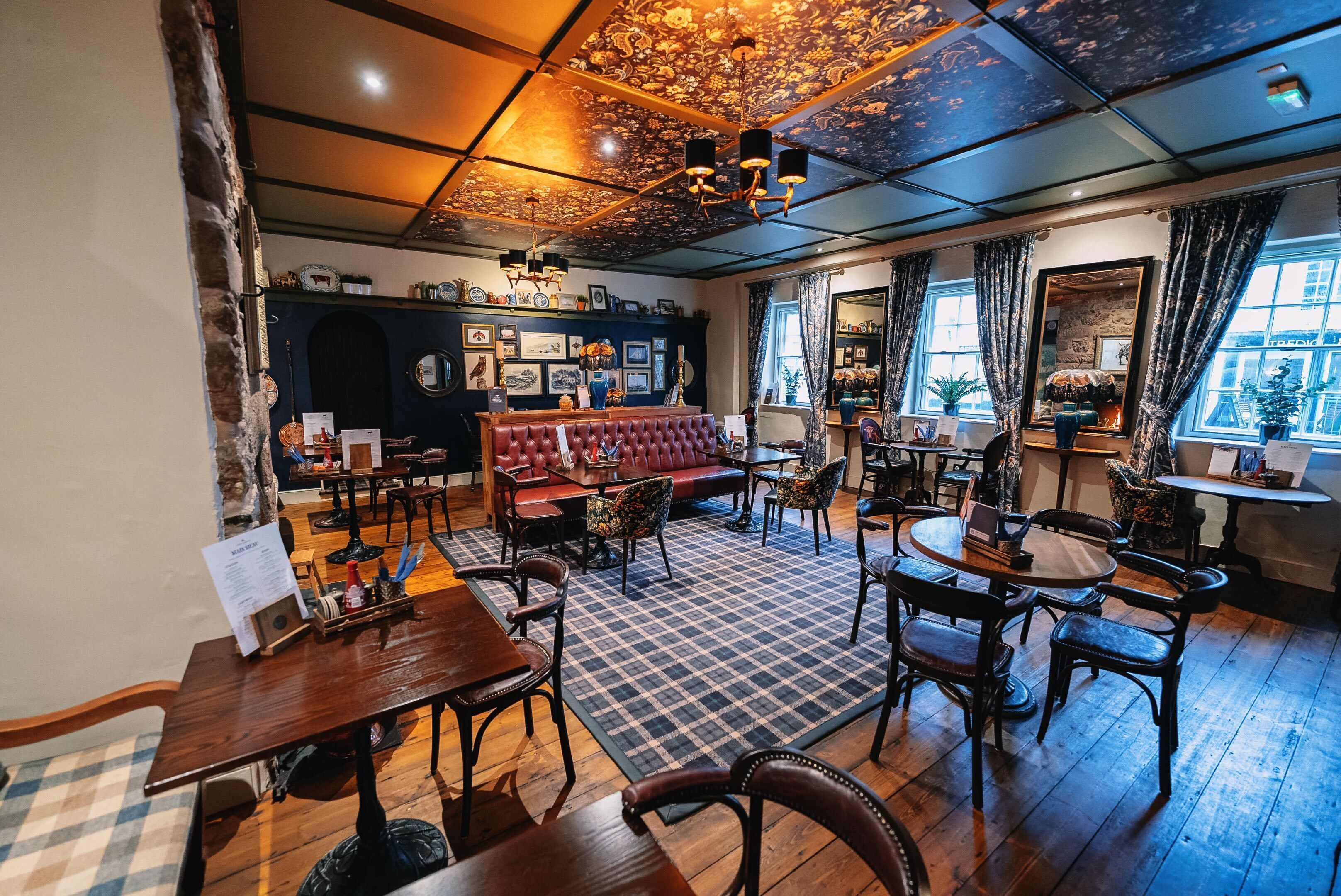 Ein gemütliches Restaurant mit Schachbrettboden, Holztischen und einer roten Couch.