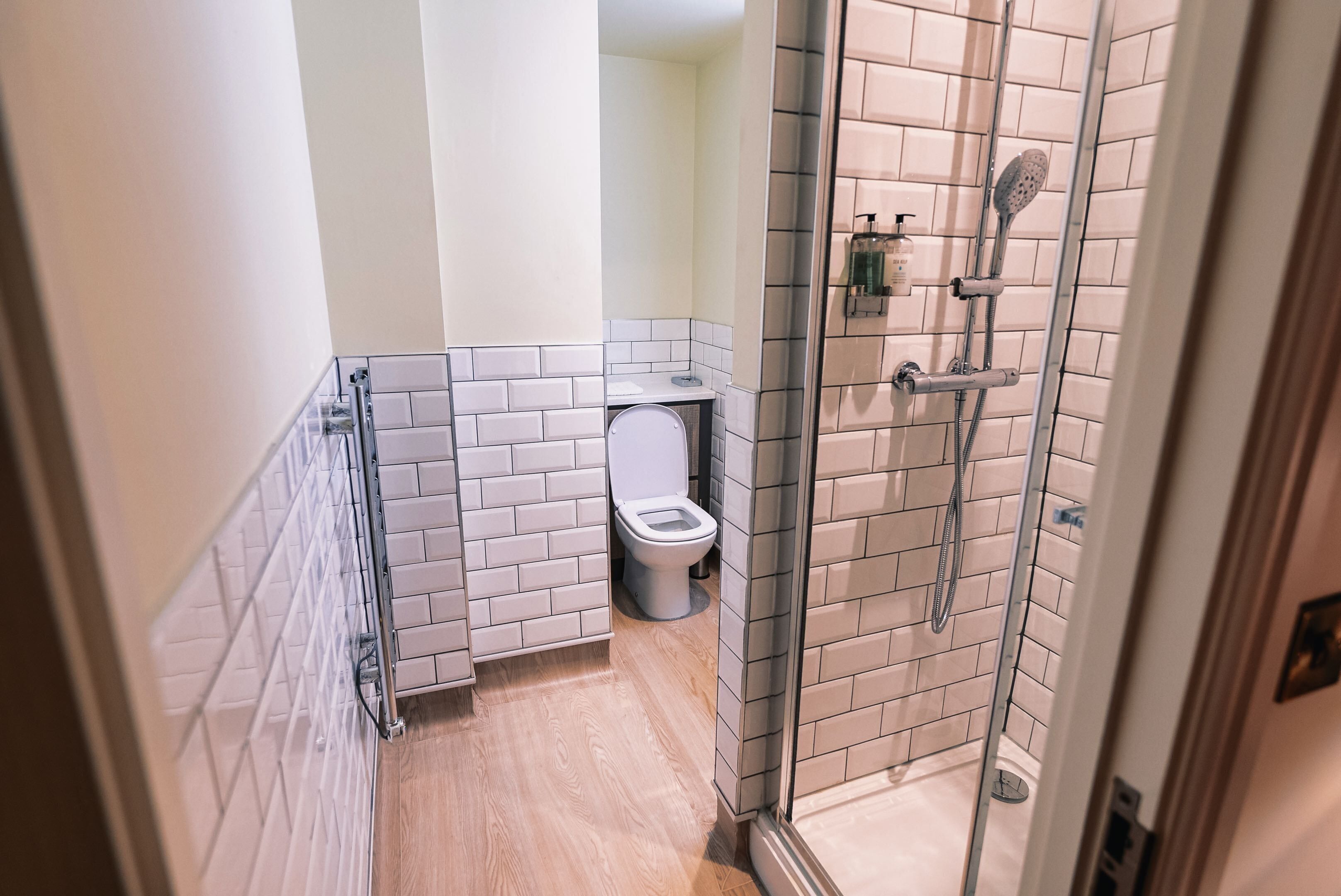 Une salle de bain avec des toilettes, une douche dotée d’une porte en verre et un sol carrelé.