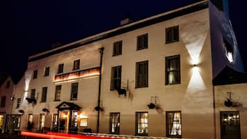 Un edificio histórico con un letrero que dice "Ye Olde Bull's Head Inn", con múltiples ventanas y una entrada tradicional.