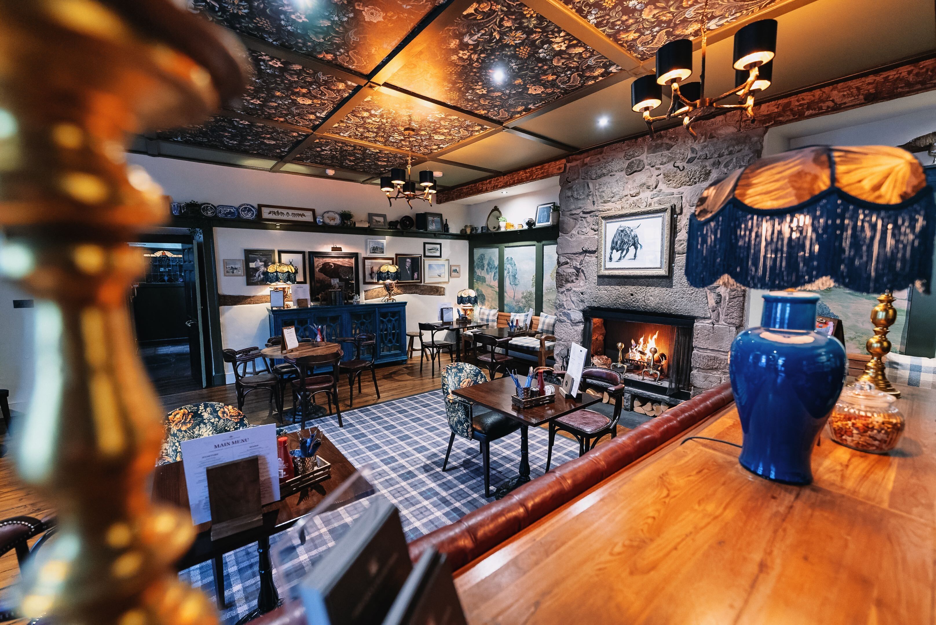 A cozy interior with a fireplace, wooden furniture, and a checkered floor.