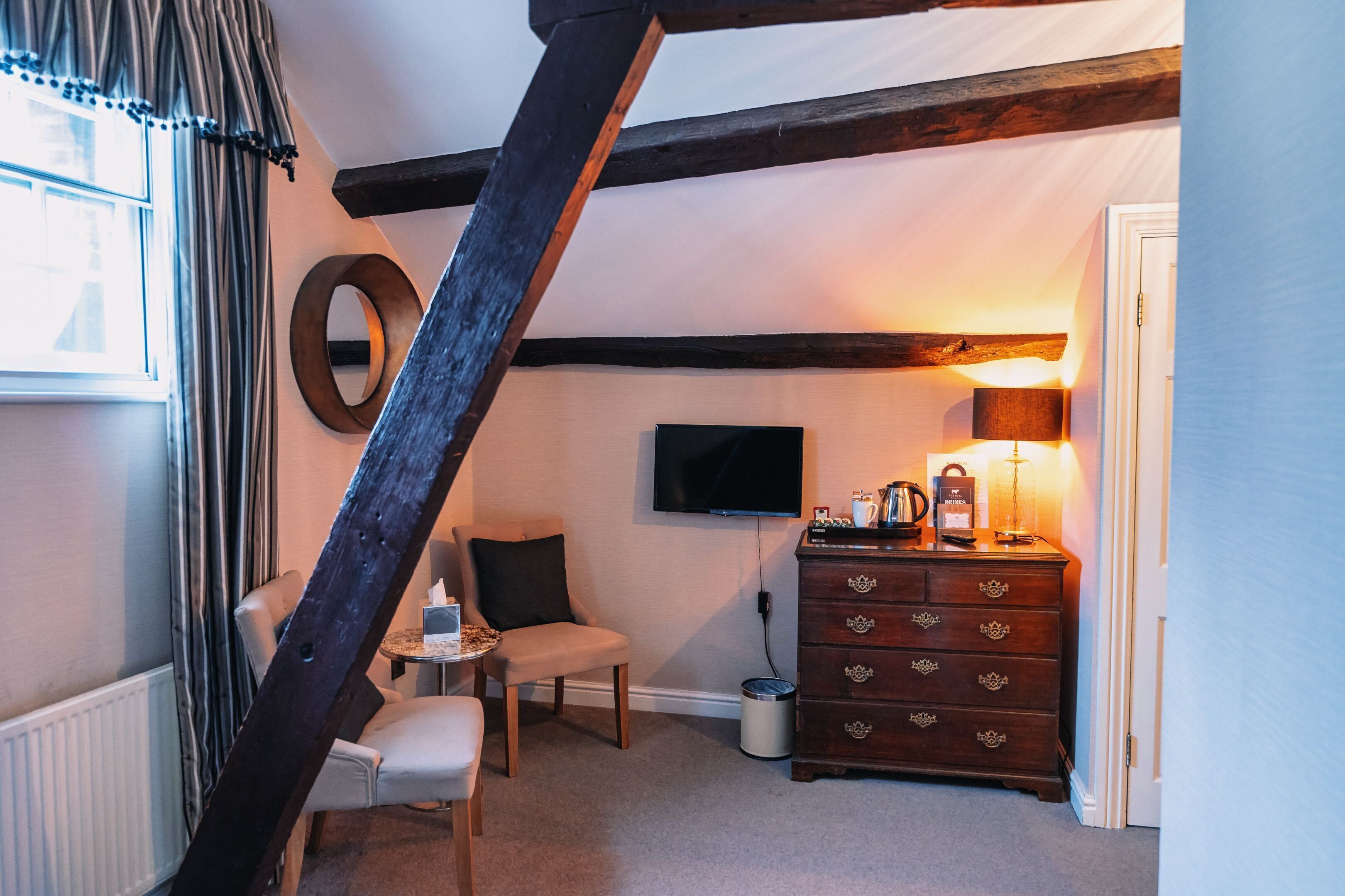 A cozy room with a wooden ceiling, a television, a dresser, and a chair.