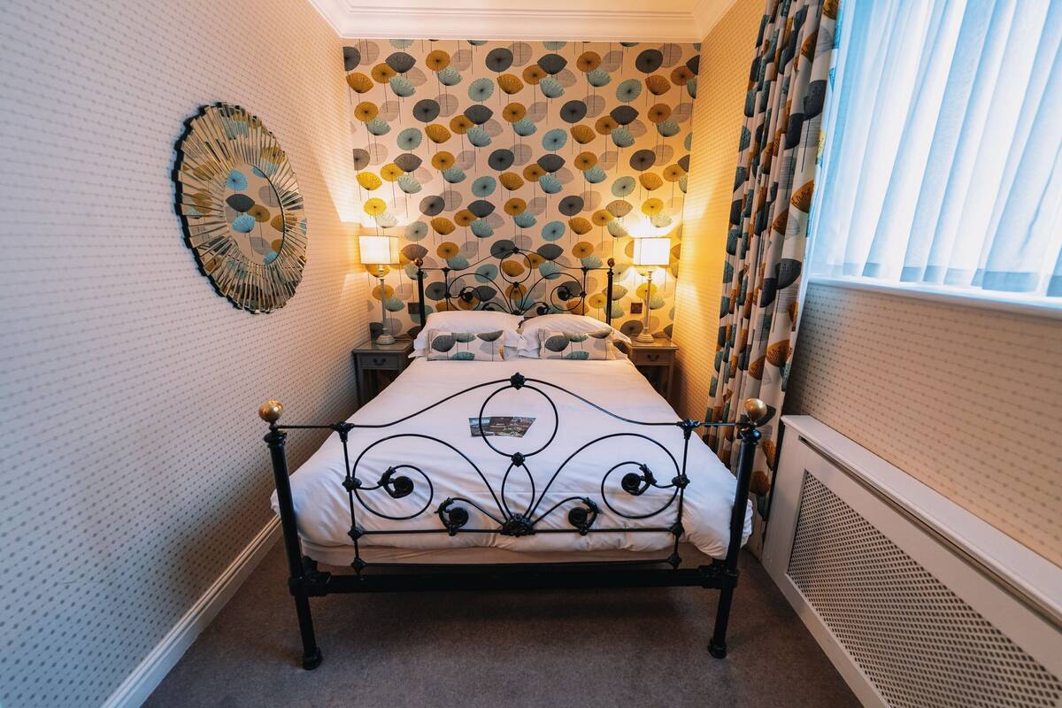 A neatly arranged bedroom with a bed, two bedside tables, and a wall clock.