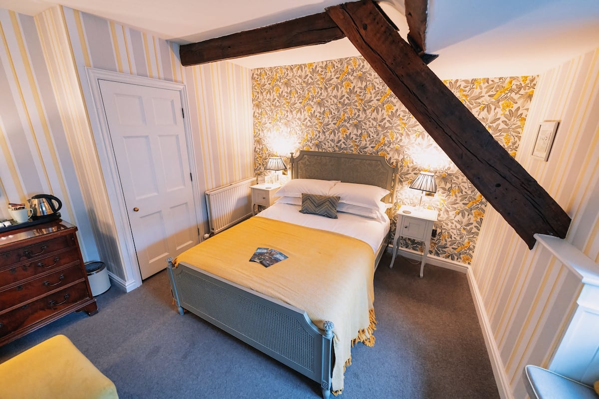 A bedroom with a bed, bedside tables, a dresser, and a radiator.
