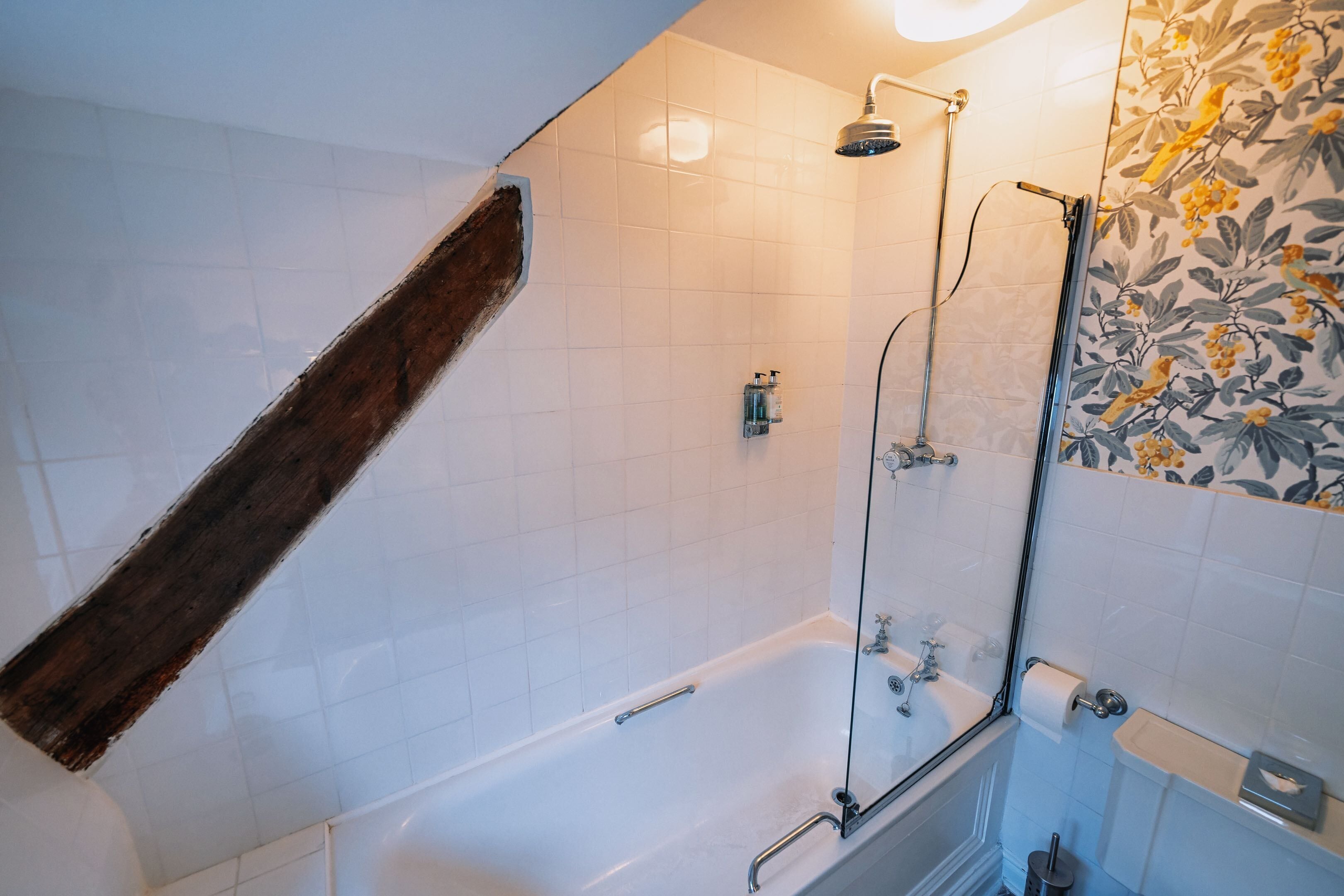 A bathroom with a bathtub, shower, and a wooden beam.