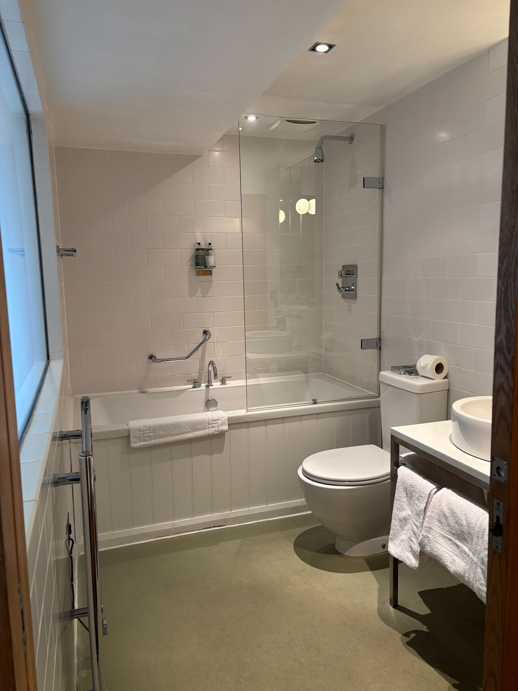 A modern bathroom with a glass-enclosed shower, a standalone bathtub, a toilet, and a sink with a mirror.