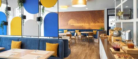 A modern restaurant interior with blue seating, wooden tables, and a counter with food and drinks.