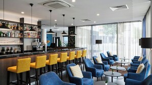 A bar area with yellow barstools, blue armchairs, and a variety of liquor bottles. - Four Points Flex by Sheraton Essen (Essen)