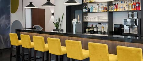 A bar area with a long counter, multiple yellow bar stools, and a variety of liquor bottles on shelves.