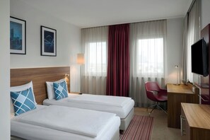 A hotel room with two beds, a desk, a chair, a television, and two framed pictures on the wall. - Four Points Flex by Sheraton Essen (Essen)