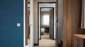 A hotel room with a bed, a wooden wardrobe, and a door leading to a bathroom. - Four Points Flex by Sheraton Essen (Essen)