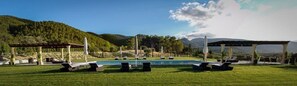 Una piscina techada, una piscina al aire libre, sombrillas