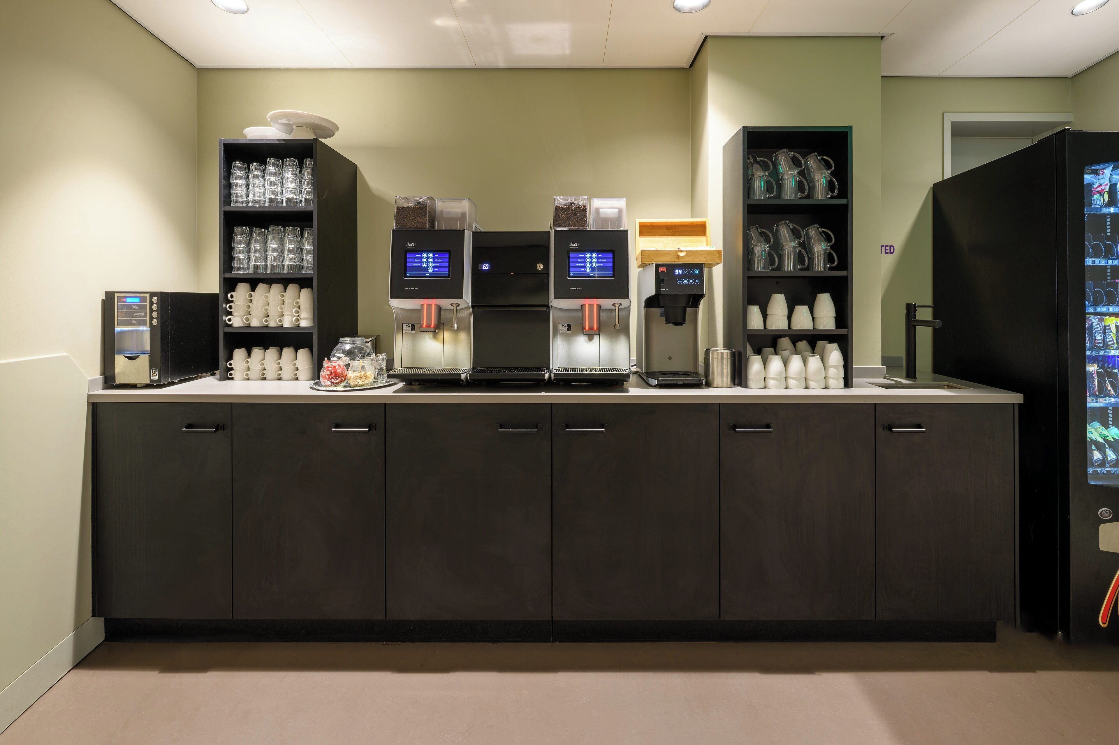 A self-service beverage station with multiple dispensers, a coffee machine, and a refrigerated display case.