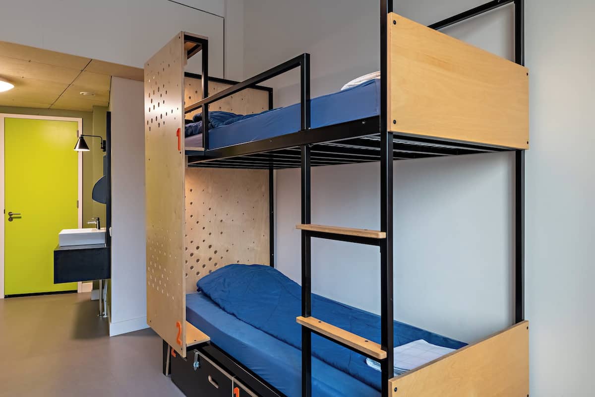 A bunk bed room with a wooden bunk, a desk, and a sink.