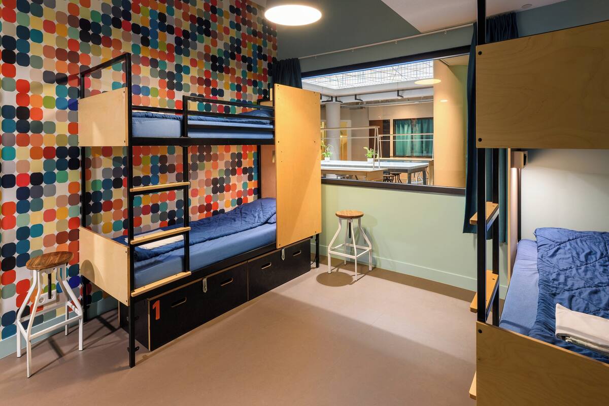 A room with bunk beds, a stool, and a colorful polka dot wall.