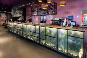 A bar area with a long counter, stools, shelves with bottles, and a refrigerator.