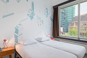 A hotel room with two beds, a nightstand with a lamp, a window with a view of buildings, and a wall with a cityscape mural. - Stayokay Utrecht Centrum - Hostel (Utrecht)