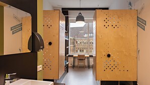 A modern bathroom with a sink, mirror, and wooden lockers. - Stayokay Utrecht Centrum - Hostel (Utrecht)