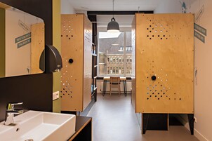 A modern bathroom with a sink, mirror, and wooden lockers.
