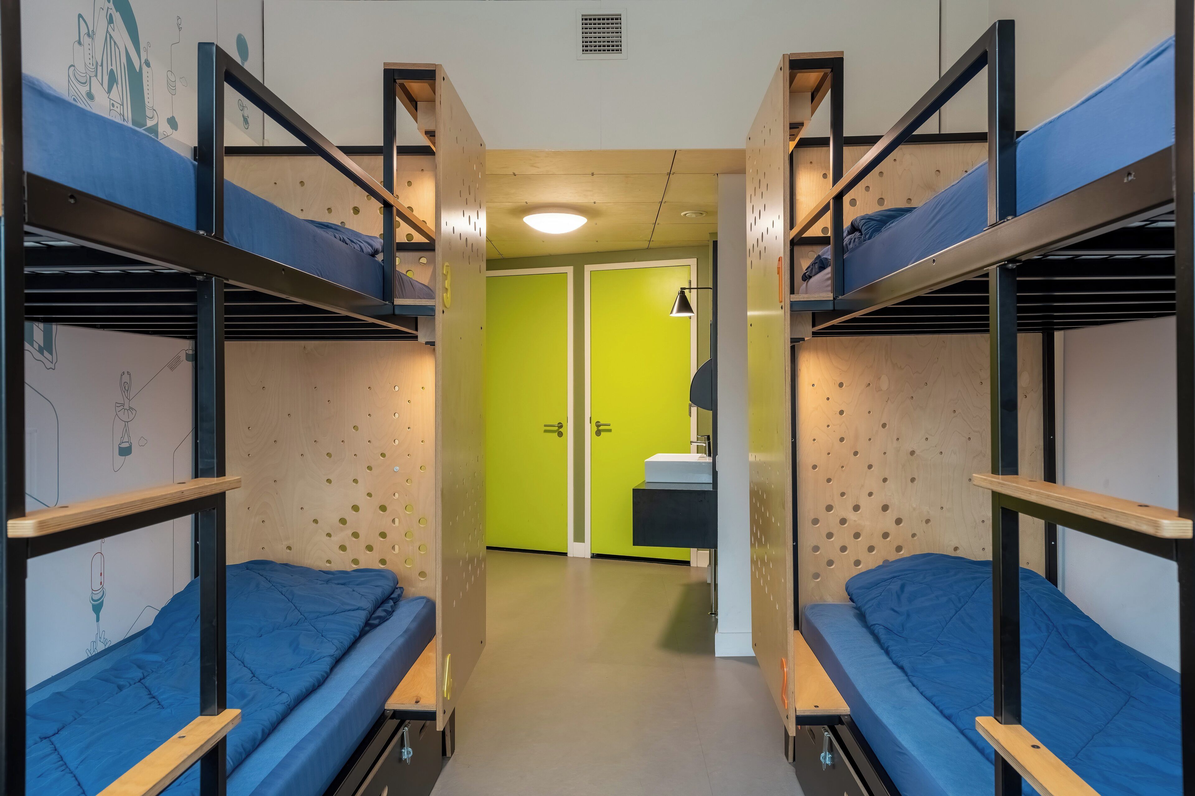 Un dormitorio con literas, un lavamanos pequeño y una puerta verde.