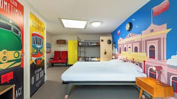 Una habitación con cama, literas, escritorio, silla, armario y un mural en la pared.