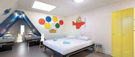 Un dormitorio infantil con literas, un tobogán y decoraciones de pared coloridas.