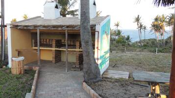 Un edificio frente a la playa con un patio de ladrillo, una mesa de madera y un letrero.