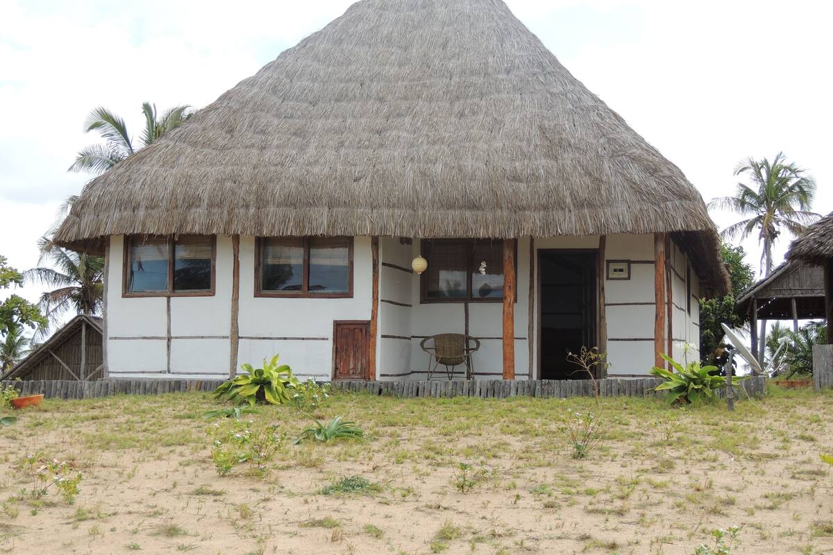 Una casa de techo de paja con un diseño sencillo, una puerta de madera y ventanas.