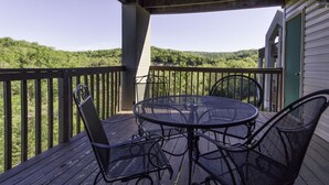 A wooden deck with a round table and two chairs, overlooking a forested hillside. - Branson Condo Resorts Silver Dollar City (Branson)