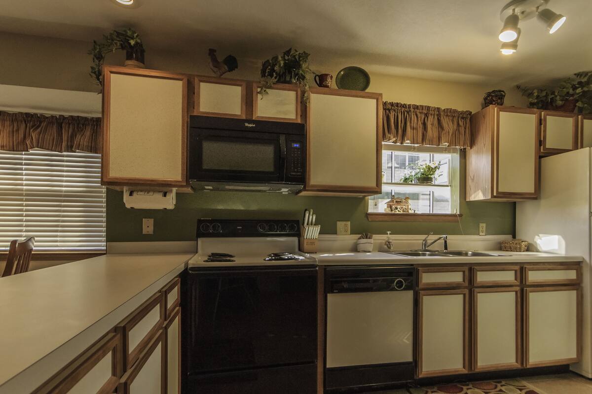 A kitchen with a stove, microwave, sink, and cabinets.