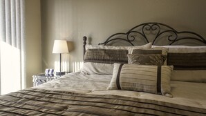 A neatly made bed with striped bedding, a headboard with a heart design, and a bedside lamp. - Branson Condo Resorts Silver Dollar City (Branson)