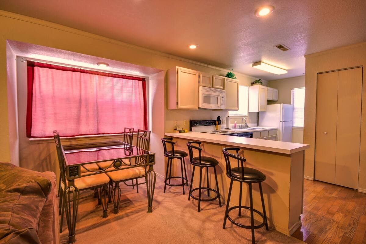 A compact kitchen with a dining area, including a bar stool setup and a dining table with chairs.