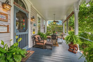 A porch with wicker furniture, a small table, and potted plants.