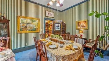 A dining room with striped wallpaper, wooden furniture, and a ceiling fan.