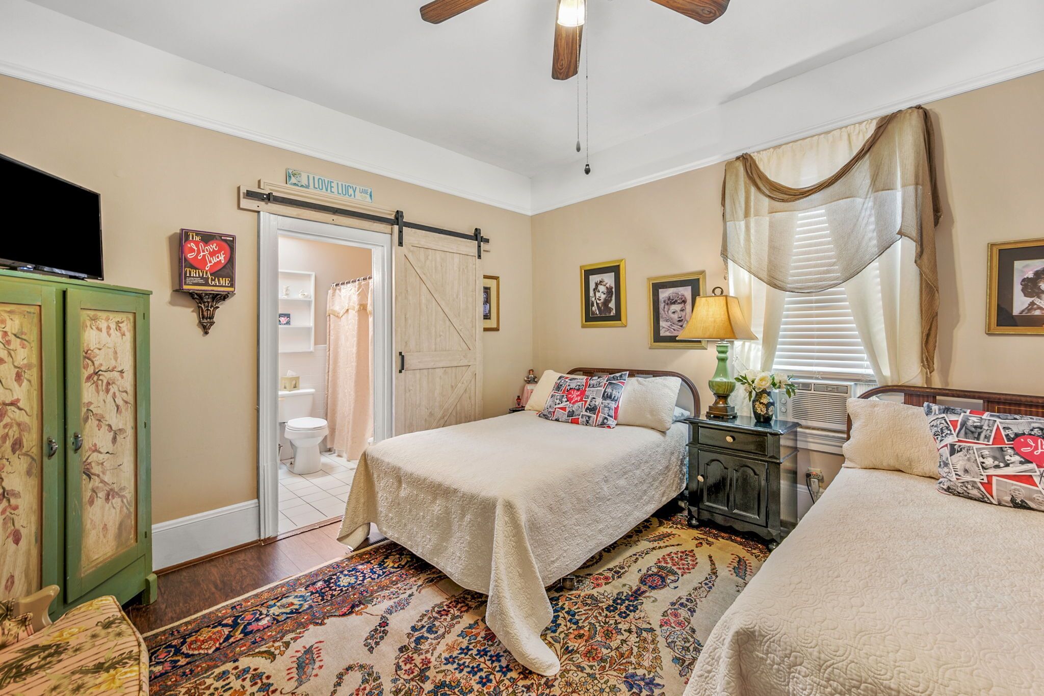 A bedroom with two beds, a television, a wardrobe, and a bathroom visible through an open door.