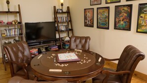 A living room with a round table, four chairs, a television, and a bookshelf with DVDs.