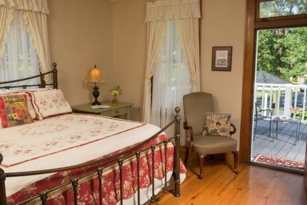 A bedroom with a bed, a chair, a nightstand, and a window with curtains.