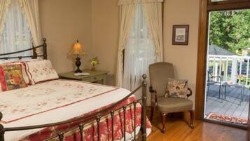 A bedroom with a bed, a chair, a nightstand, and a window with curtains.