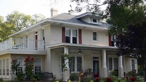 A two-story house with a balcony, a front porch, and a well-maintained garden.