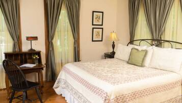 A bedroom with a bed, a desk, and a chair. There are two lamps on the nightstands.