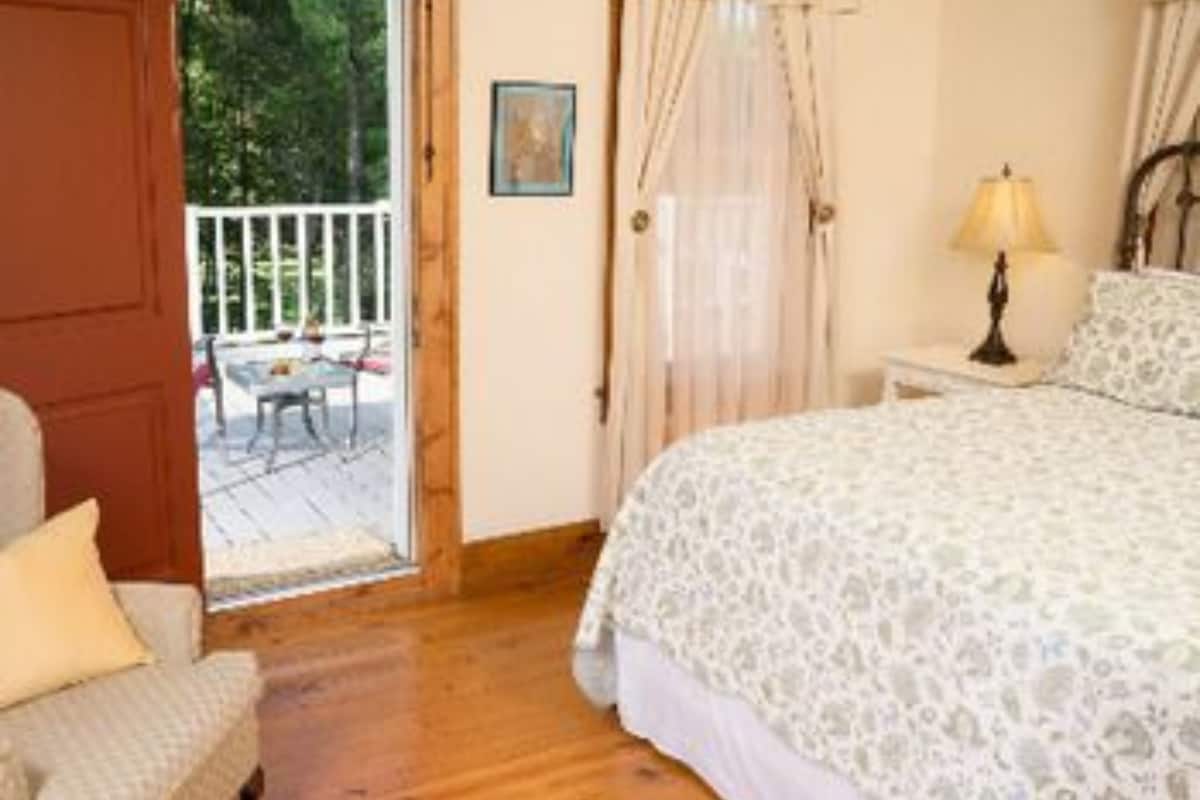 A bedroom with a bed, a chair, a nightstand, and a window with curtains.