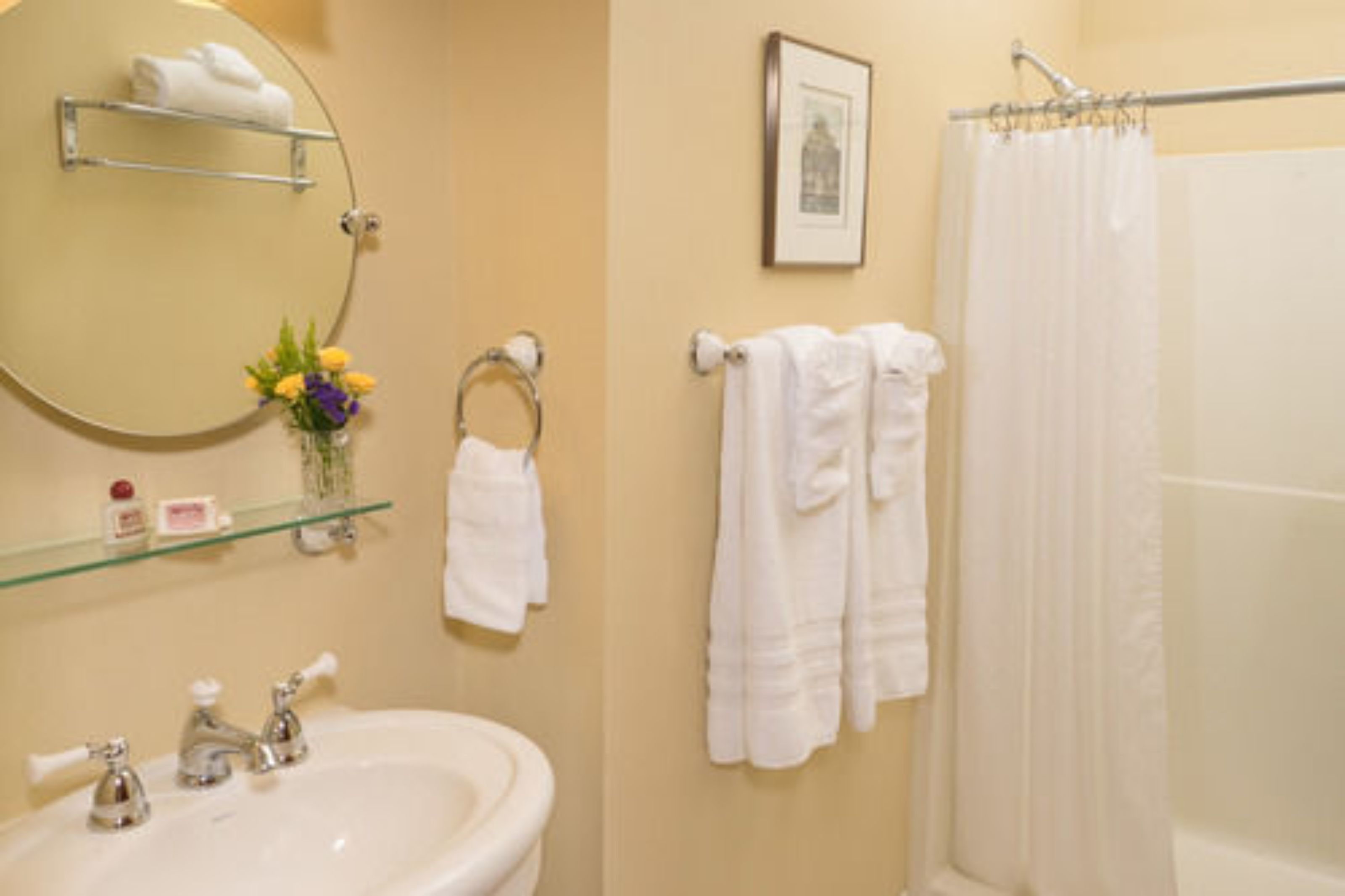 A bathroom with a round mirror, a sink, a towel rack, and a shower curtain.