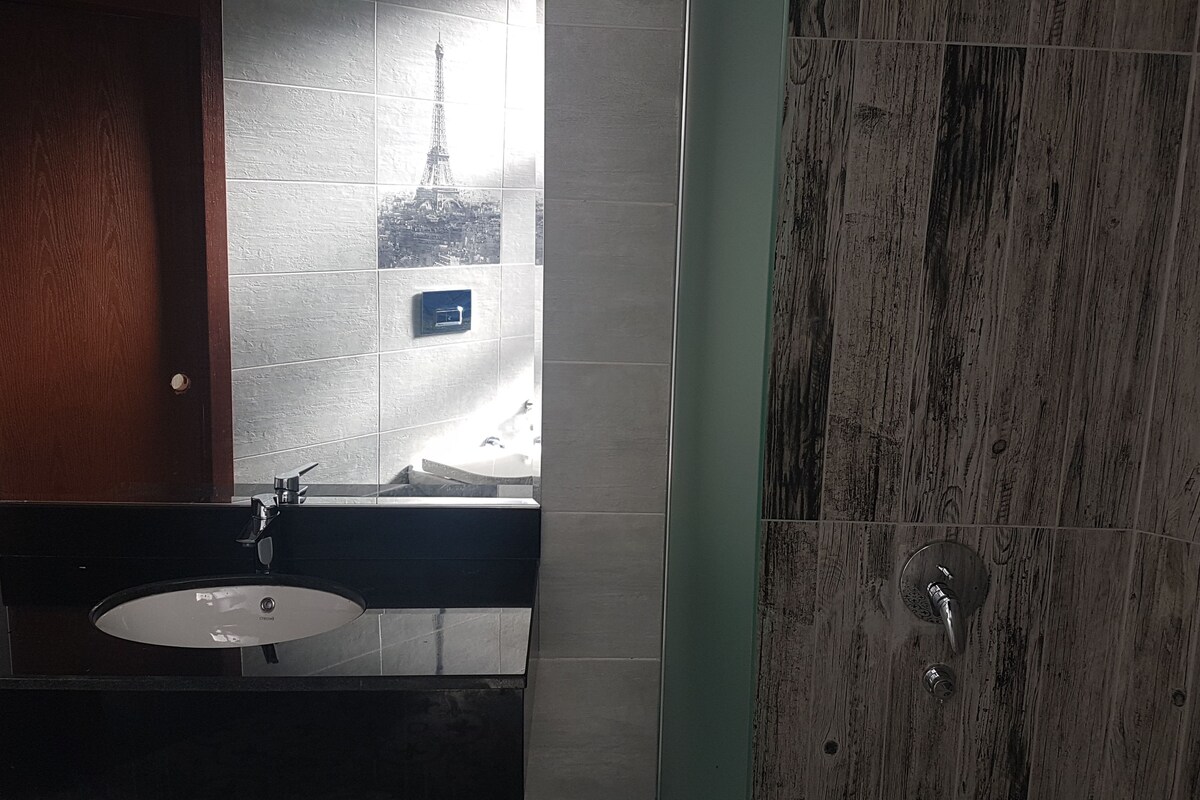 A bathroom with a sink, mirror, and a wooden door.