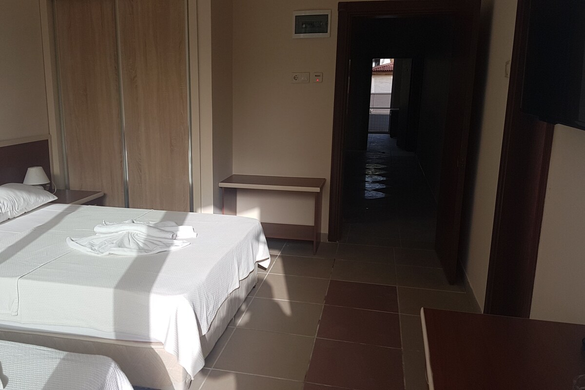 A hotel room with a bed, a nightstand, a desk, and a bathroom visible through an open door.
