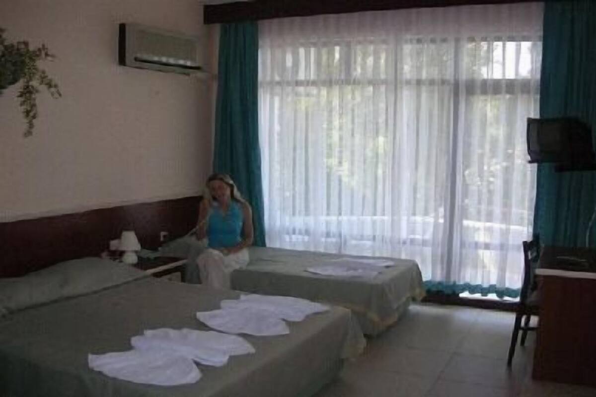 Habitación de hotel con dos camas, un escritorio, una silla y un televisor.